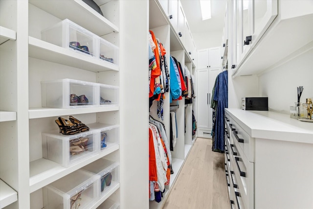 walk in closet with light wood finished floors
