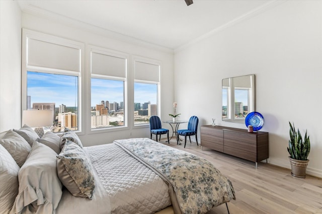 bedroom featuring ornamental molding, a view of skyline, light wood-type flooring, and baseboards