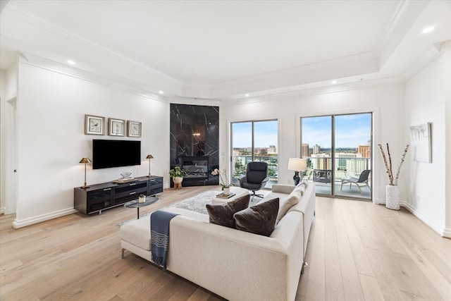 living room with a tray ceiling, crown molding, light wood-style flooring, recessed lighting, and baseboards