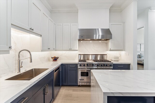 kitchen featuring appliances with stainless steel finishes, a sink, ornamental molding, light wood finished floors, and decorative backsplash
