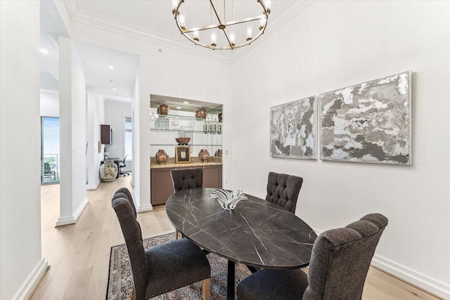 dining area with light wood-type flooring, a chandelier, crown molding, and baseboards