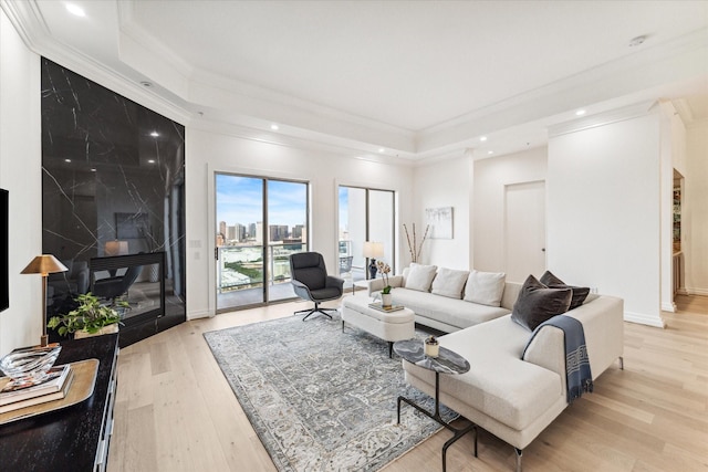 living area featuring crown molding, a raised ceiling, light wood-style floors, and recessed lighting