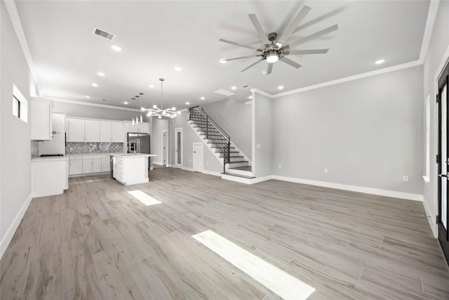 unfurnished living room featuring ornamental molding, recessed lighting, a chandelier, stairs, and a ceiling fan