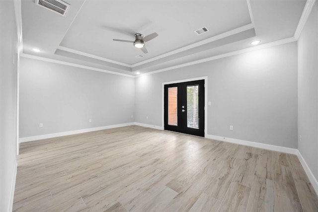 empty room featuring a tray ceiling, french doors, a ceiling fan, crown molding, and baseboards