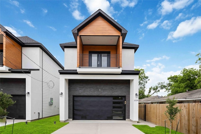 contemporary house with a balcony, fence, an attached garage, and driveway