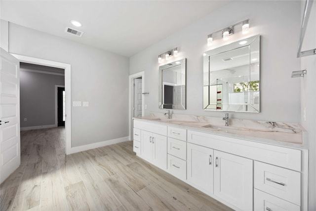 full bathroom featuring double vanity, baseboards, wood finished floors, and a shower