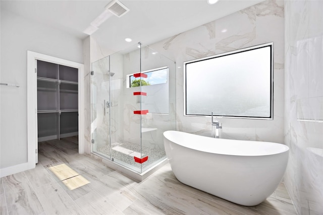 bathroom with a marble finish shower, a soaking tub, a spacious closet, and recessed lighting