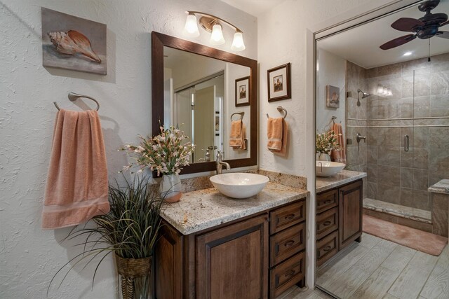 104 Smith Ln, League City, TX 77573 - full bathroom with a stall shower, a ceiling fan, two vanities, a textured wall, and wood finished floors