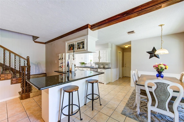 1223 Green Briar Dr, Huntsville, TX 77340 - kitchen featuring light tile patterned floors, white cabinets, a breakfast bar, a sink, and a textured ceiling