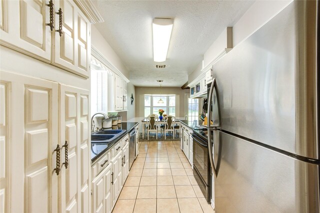1223 Green Briar Dr, Huntsville, TX 77340 - kitchen featuring stainless steel appliances, a sink, dark countertops, a textured ceiling, and light tile patterned floors
