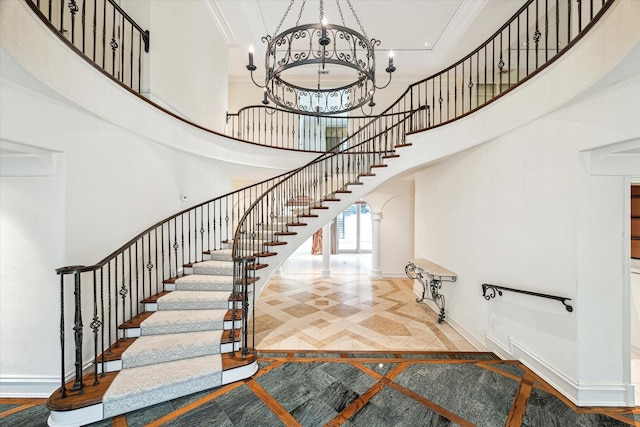 8618 Stable Crest Blvd, Houston, TX 77024 - stairway featuring baseboards, a high ceiling, arched walkways, inlaid floor details, and a chandelier