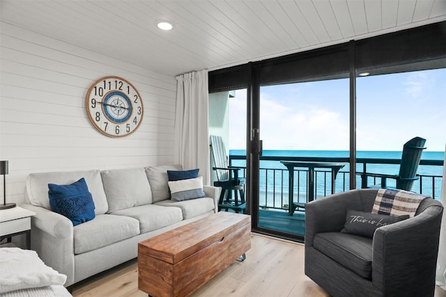 5220 Seawall Blvd Unit 1231, Galveston, TX 77551 - living room featuring a wall of windows, light wood-type flooring, wood walls, a water view, and wooden ceiling