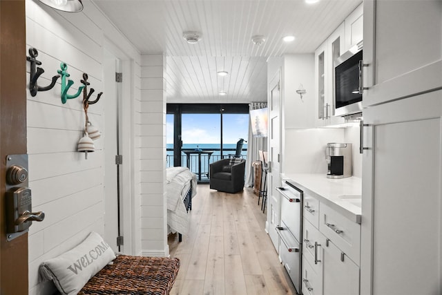 5220 Seawall Blvd Unit 1231, Galveston, TX 77551 - kitchen with a water view, white cabinetry, light countertops, expansive windows, and light wood finished floors