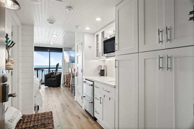 5220 Seawall Blvd Unit 1231, Galveston, TX 77551 - kitchen with stainless steel appliances, floor to ceiling windows, light countertops, light wood-style floors, and white cabinets