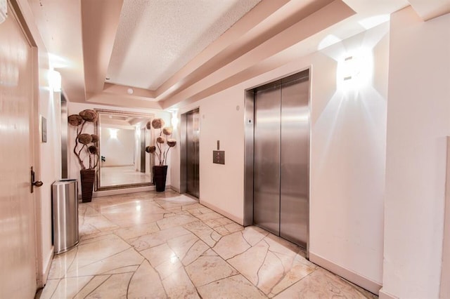 5220 Seawall Blvd Unit 1231, Galveston, TX 77551 - hall with elevator, baseboards, a tray ceiling, light marble finish flooring, and a textured ceiling