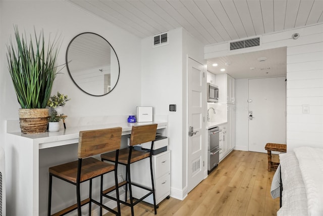 5220 Seawall Blvd Unit 1231, Galveston, TX 77551 - interior space with light wood-style flooring, light countertops, stainless steel microwave, white cabinets, and a kitchen bar