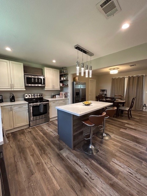 kitchen featuring stainless steel appliances, light countertops, dark wood-style flooring, a breakfast bar, and recessed lighting