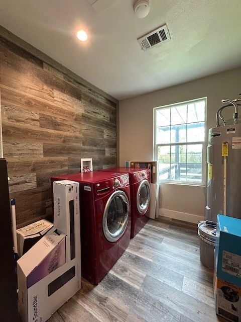 washroom featuring washer and clothes dryer, wood walls, wood finished floors, water heater, and recessed lighting