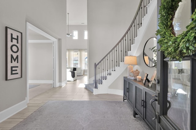 foyer entrance featuring stairs, baseboards, wood finished floors, and a high ceiling