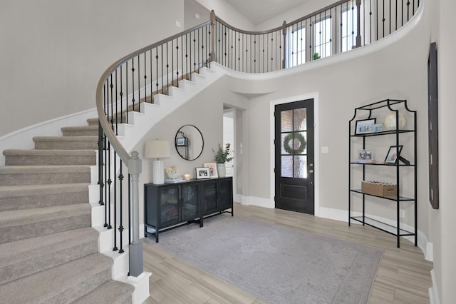 entryway featuring a towering ceiling, stairs, healthy amount of natural light, and wood finished floors