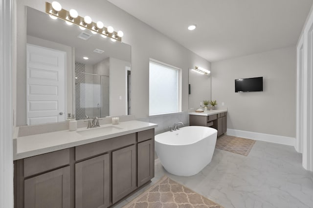 full bath featuring a shower stall, marble look tiles, two vanities, a freestanding tub, and baseboards