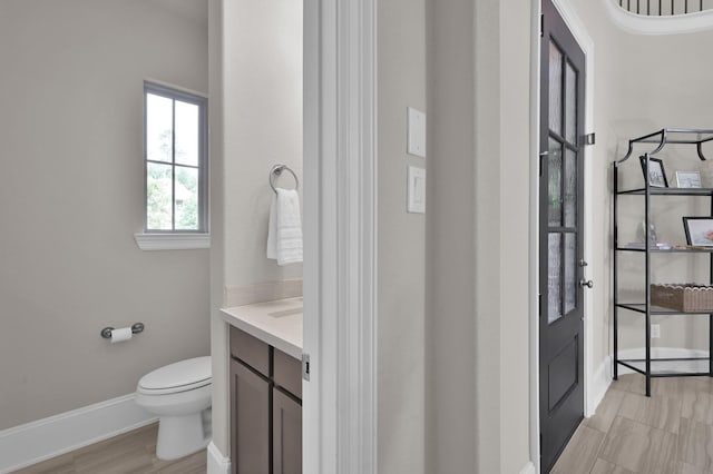 bathroom with toilet, vanity, and baseboards