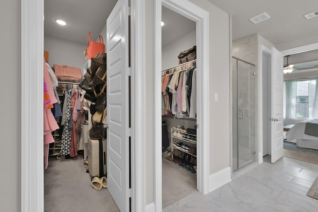 spacious closet featuring light marble finish floors and a ceiling fan