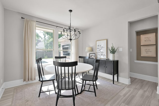 dining area with a chandelier, baseboards, and light wood finished floors