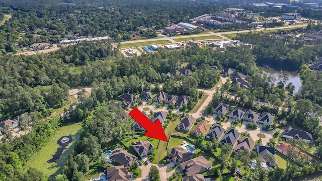aerial view of property and surrounding area with a heavily wooded area and nearby suburban area