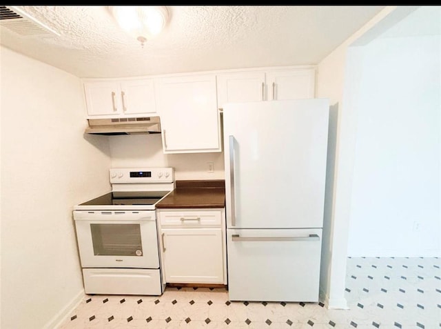 kitchen featuring white appliances, under cabinet range hood, light flooring, dark countertops, and a textured ceiling
