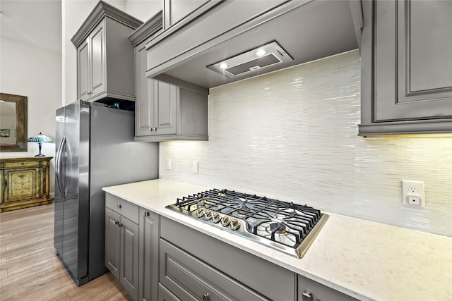 907 Falcon Hollow Ln, Pinehurst, TX 77362 - kitchen with gray cabinets, appliances with stainless steel finishes, light wood-style floors, and decorative backsplash