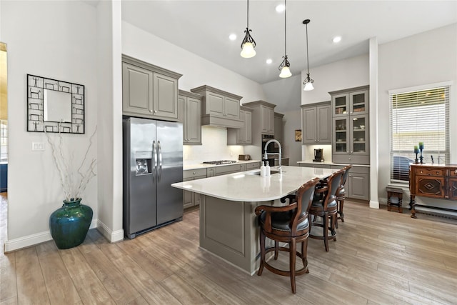 907 Falcon Hollow Ln, Pinehurst, TX 77362 - kitchen featuring appliances with stainless steel finishes, gray cabinets, light countertops, decorative backsplash, and a kitchen island with sink