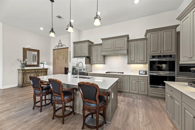 907 Falcon Hollow Ln, Pinehurst, TX 77362 - kitchen with gray cabinetry, appliances with stainless steel finishes, a sink, decorative backsplash, and light countertops