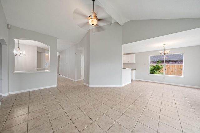 unfurnished living room featuring a chandelier, vaulted ceiling, light tile patterned floors, ceiling fan, and arched walkways