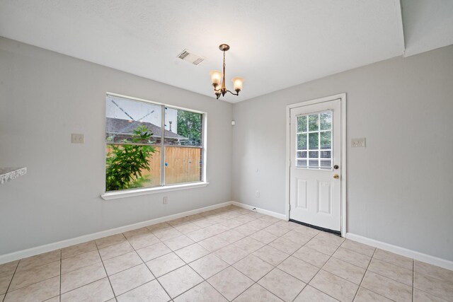 spare room featuring healthy amount of natural light, a chandelier, and baseboards