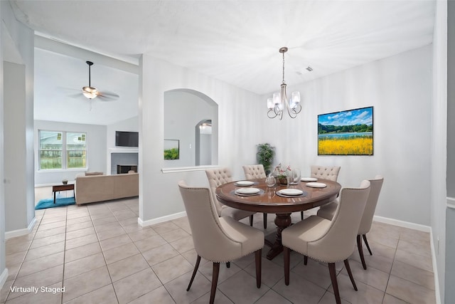 dining room featuring light tile patterned flooring, arched walkways, baseboards, a chandelier, and vaulted ceiling