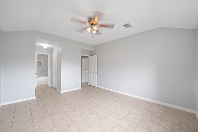 unfurnished room with ceiling fan, vaulted ceiling, light tile patterned flooring, and baseboards