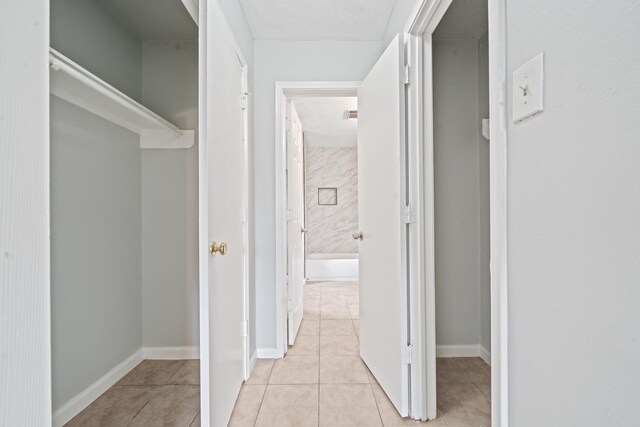 corridor with light tile patterned flooring and baseboards