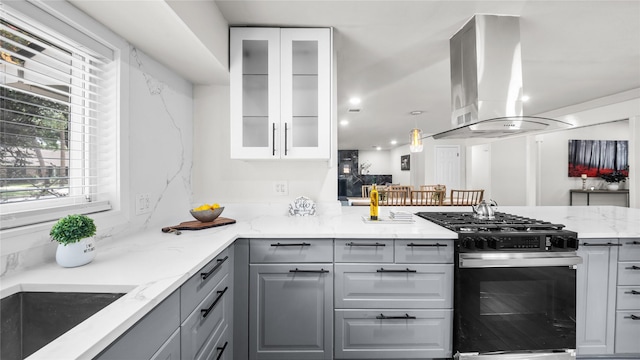 9210 Linkmeadow Ln, Houston, TX 77025 - kitchen featuring gas range, island exhaust hood, gray cabinetry, light stone countertops, and glass insert cabinets