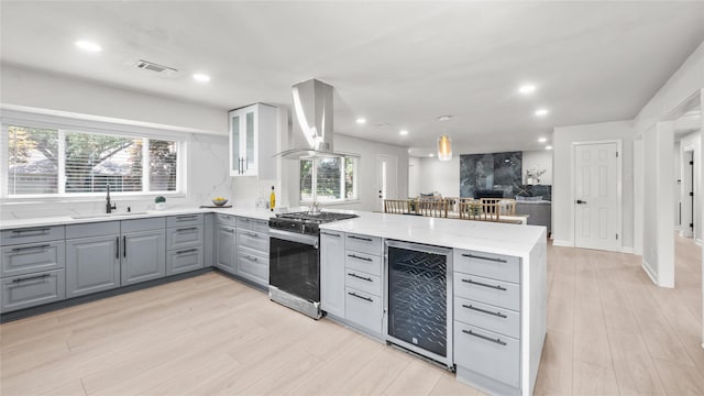 9210 Linkmeadow Ln, Houston, TX 77025 - kitchen featuring gray cabinetry, gas range, wine cooler, wall chimney exhaust hood, and a sink