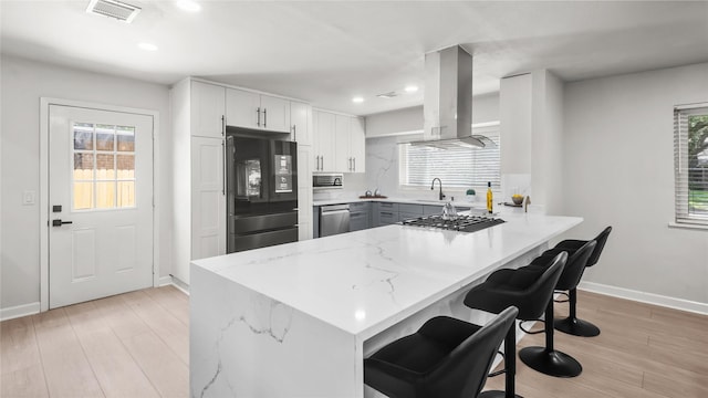9210 Linkmeadow Ln, Houston, TX 77025 - kitchen featuring stainless steel appliances, island exhaust hood, a peninsula, baseboards, and light stone counters