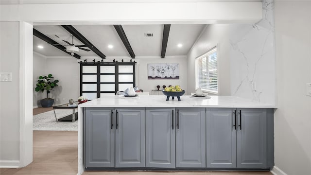 9210 Linkmeadow Ln, Houston, TX 77025 - kitchen featuring gray cabinetry, beam ceiling, light wood-style floors, a barn door, and a peninsula