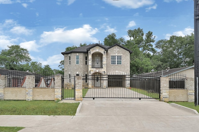 french country style house featuring concrete driveway, a gate, a fenced front yard, and stone siding