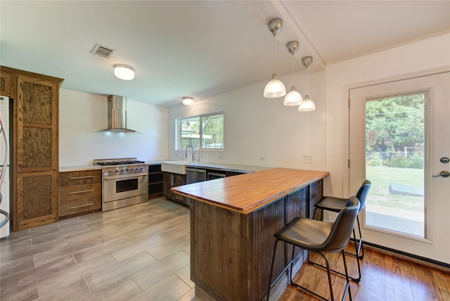 4538 Warm Springs Rd, Houston, TX 77035 - kitchen featuring appliances with stainless steel finishes, wall chimney exhaust hood, a peninsula, a kitchen breakfast bar, and pendant lighting