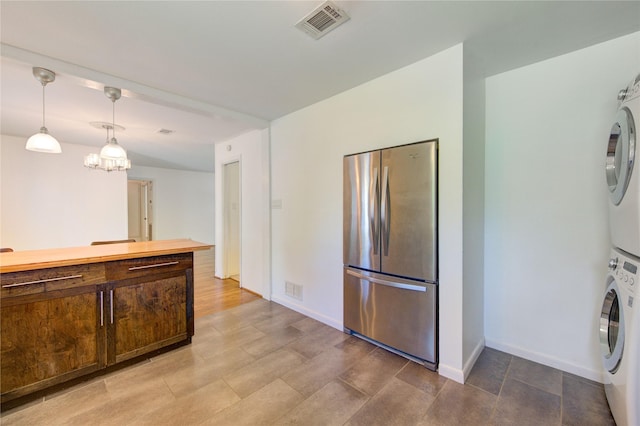 4538 Warm Springs Rd, Houston, TX 77035 - kitchen with freestanding refrigerator, stacked washer / drying machine, dark brown cabinetry, hanging light fixtures, and baseboards