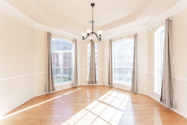 unfurnished room with wood finished floors, a chandelier, and a tray ceiling