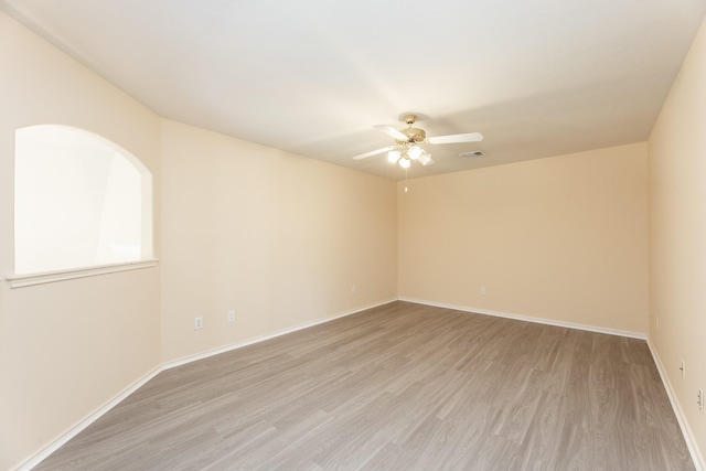 empty room featuring light wood finished floors, ceiling fan, and baseboards