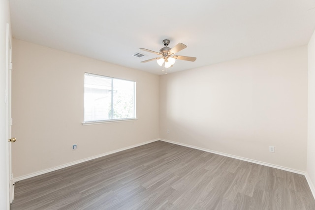 spare room featuring light wood-type flooring, ceiling fan, and baseboards
