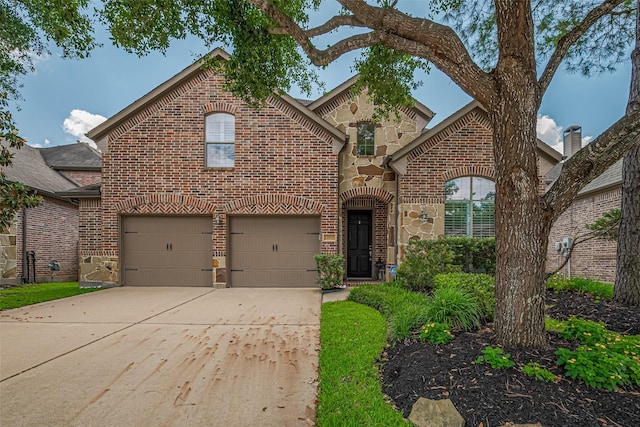 view of front of property with brick siding, driveway, an attached garage, and stone siding