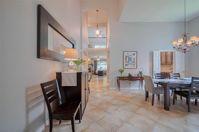 dining area with a chandelier, a towering ceiling, baseboards, and light tile patterned floors